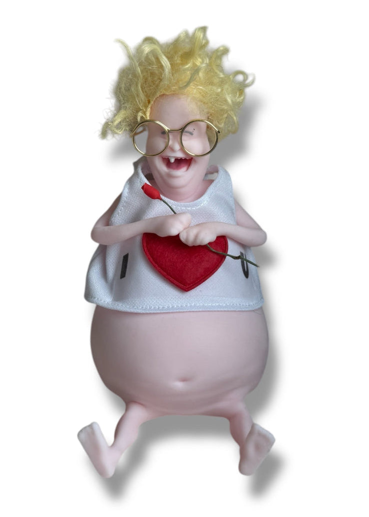A doll with dark hair, wearing glasses and a white shirt with the text 'I Love U' holding a miniature rose.
